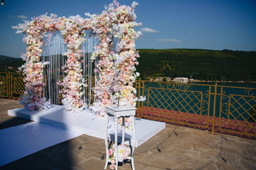 The concept of wedding decor, street decoration, wedding arch is decorated with flowers - pink and white peonies. Wedding day, ceremony place for the bride and groom, decor, flowers, florists.