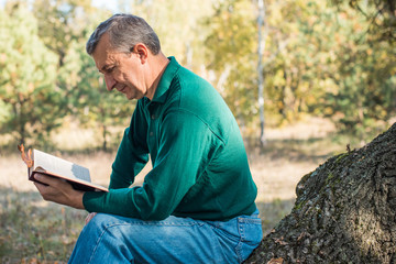 Older European senior man with a good mood in forest, outdoor portrait. The concept of life after 50 years 