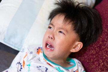 A sad boy is crying, he doesn't want to go to bed at night.