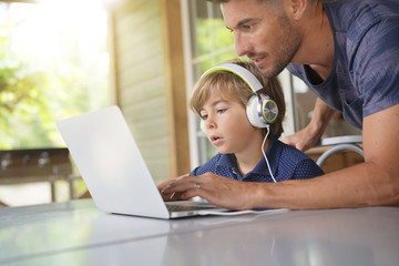 Little boy using laptop with help of daddy © goodluz