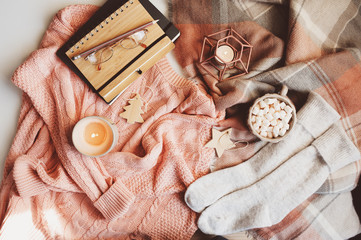 cozy winter or Christmas table with seasonal fashion clothes, hot cocoa and candles. Hygge concept