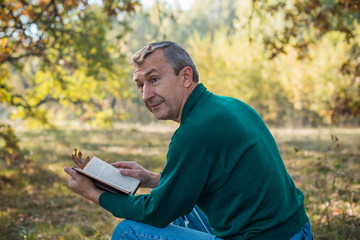 Older European senior man with a good mood in forest, outdoor portrait. The concept of life after 50 years 