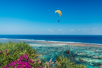 Shore and blue ocean with paraglider in tropical island.