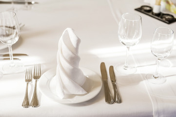 Spun white napkins on a white plate on a served table. Plate in a cafe or restaurant with a napkin...