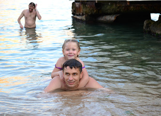a man with a child happily swim in the sea  