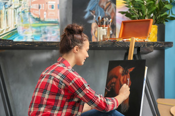 Female artist painting picture in workshop
