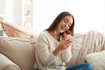 Beautiful young woman listening to music at home