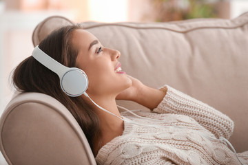 Beautiful young woman listening to music at home
