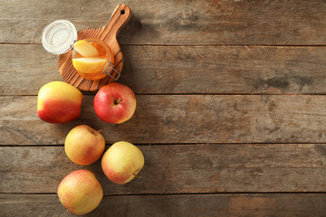 Ripe juicy apples with honey on wooden table