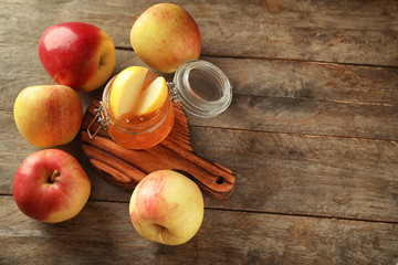 Ripe juicy apples with honey on wooden table