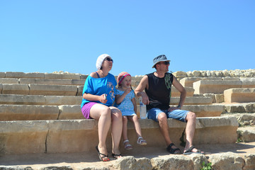 the family sits on the bench of the street amphitheater and look into the distance 