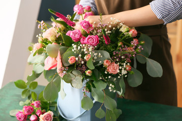 Female florist preparing box with beautiful flowers at table
