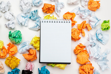 Office workspace with an empty notebook, crumpled paper