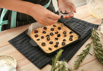 Woman preparing traditional Italian Focaccia on wooden table