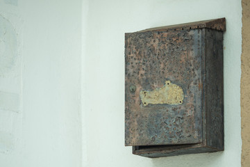An old, rusty mailbox hangs open on the wall
