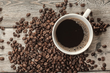 Cup of coffee and beans on wooden background