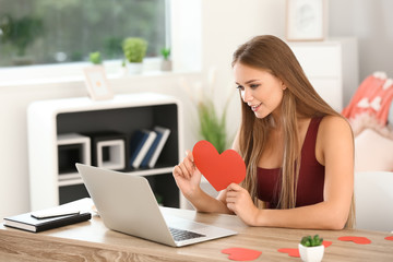 Young woman with laptop having online dating at home