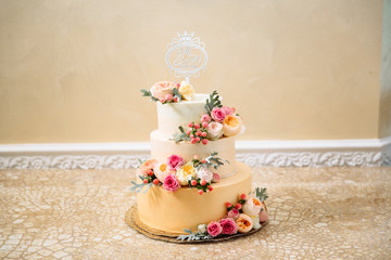 Golden wedding three-story cake. Close-up of a delicious dessert decorated with flowers, wedding...