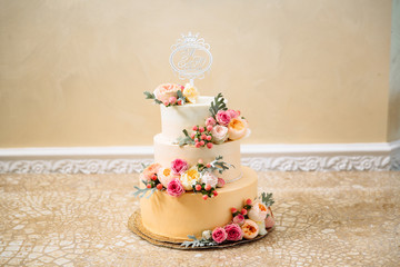 Golden wedding three-story cake. Close-up of a delicious dessert decorated with flowers, wedding cake decor. Copy space
