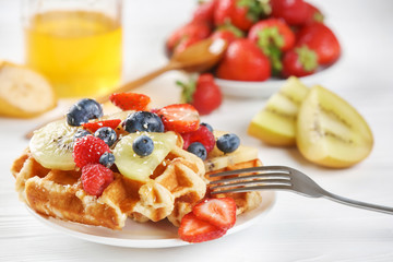 Delicious waffles with berries and kiwi slices on plate