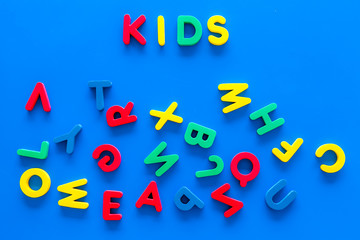 Early childhood development concept. Word kids written by plastic letters of toy alphabet on blue background top view