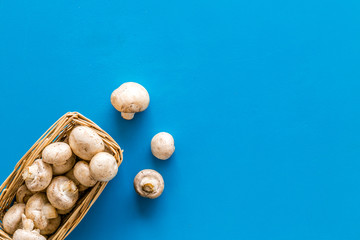 Mushroom champignons. Fresh raw whole champignons in basket on blue background top view copy space