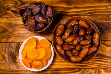 Date fruits and dried apricots on wooden table. Top view
