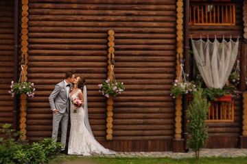 Rustic wedding. Stylish bride and groom in love, wedding couple kissing on wooden background.