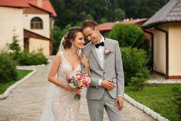 Wedding couple. Happy bride with wedding bouquet holds the groom's arm. Stylish newlywed couple....