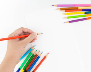 Hand holding red pencil to sketching and drawing with the set of colour pencils at the corner of blank drawing paper for kids study and learn art when back school.