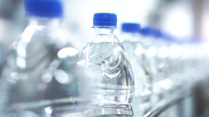 Clean water in plastic bottle moves through conveyor factory.