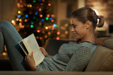Smiling woman reading a book on Christmas Eve