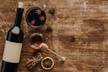 top view of mulled wine, honey and wine bottle on wooden table