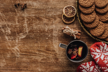 top view of mulled wine in cup, mittens and cookies on wooden tabletop, christmas concept