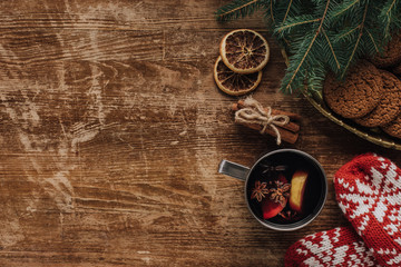 elevated view of mulled wine in cup, mittens and cookies on wooden tabletop, christmas concept