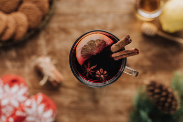 top view of mulled wine with cinnamon sticks and lemon in glass on wooden tabletop, christmas concept