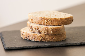 Slices of homemade multigrain bread on black slate board