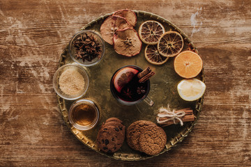 top view of mulled wine in cup and cookies on round tray on wooden table