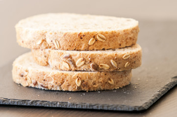 Slices of homemade multigrain bread on black slate board