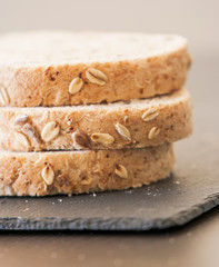 Slices of homemade multigrain bread on black slate board