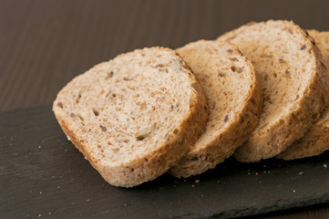 Slices of homemade multigrain bread on black slate board