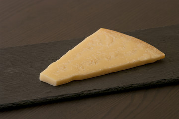 Slice of cheese on black slate board, close-up