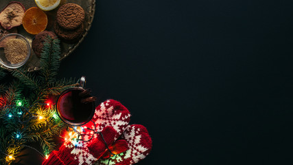 elevated view of cup of mulled wine, garland, mittens and cookies isolated on black, christmas...