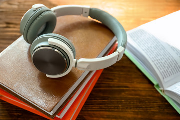 Modern headphones and books on wooden table. Concept of audiobook