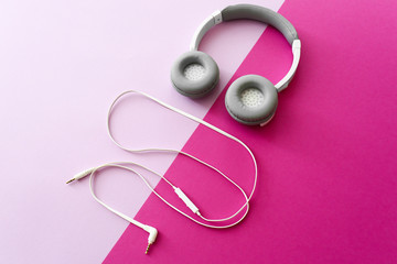 Modern headphones and earphones on color background