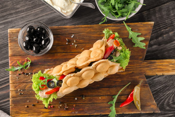 Delicious bubble waffle with meat and vegetables on wooden board