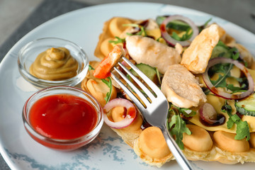Delicious bubble waffle with meat and sauces on plate, closeup