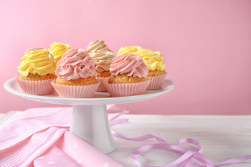 Stand with delicious cupcakes on table