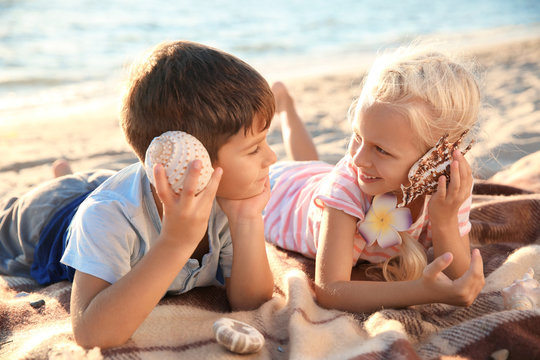 Cute little children with sea shells on beach