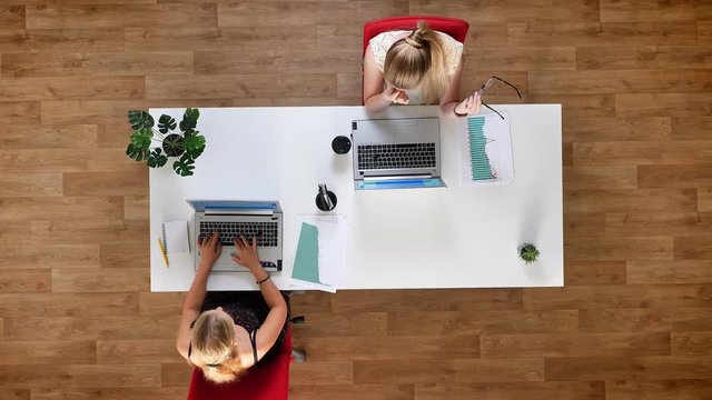 Top shot, two colleagues woman using theis working devices, scrolling on laptops concenrated